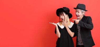 Cadılar Bayramı kostümlü Asyalı cadı kadın ve erkek. Turuncu arka planda izole edilmiş bir işaret var..