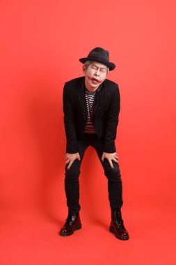 Cadılar Bayramı kostümlü Asyalı son sınıf öğrencisi. Turuncu arka planda, bitkin ve tembellik dolu bir jest..