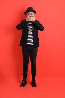 Cadılar Bayramı kostümlü Asyalı son sınıf öğrencisi Mouth 'un jestleriyle turuncu arka planda izole edilmiş sessiz bir jest..