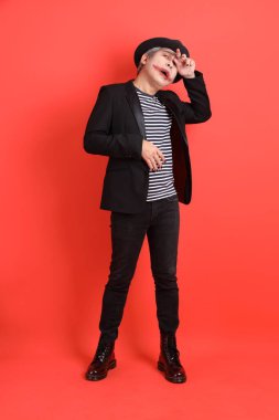 Cadılar Bayramı kostümlü Asyalı son sınıf öğrencisi turuncu arka planda kendini izole edilmiş hissediyor..