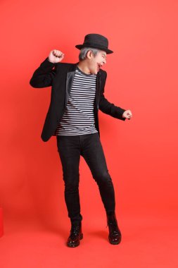 Cadılar Bayramı kostümlü Asyalı son sınıf öğrencisi turuncu arka planda izole edilmiş dans hareketleriyle.