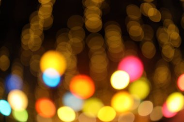 Bokeh, soyut şenlikli noel dokusu, altın bokeh parçacıkları ve koyu arkaplanda gölgeler.