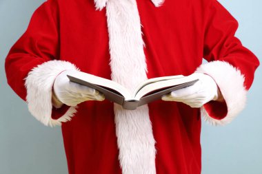 Mutlu Noeller, neşeli son sınıf öğrencisi kış tatilini kutluyor. Elinde bir kitap var. Sarı ve mavi arka planda Noel Baba kostümü giyiyor. Mutlu Noeller.