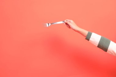 Kırmızı arka planda izole edilmiş yeşil çizgili kazak ya da çatal ya da kaşık tutan bir el ya da hediye kutusu. Mutlu Noeller..