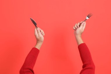 Kırmızı bir hırka giyen, elinde çatal ya da bıçak tutan kırmızı bir el. Kırmızı arka planda izole edilmiş. Mutlu Noeller..