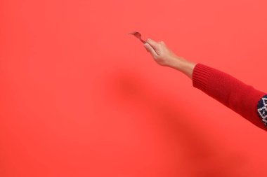 Kırmızı bir hırka giymiş, çatal tutan kırmızı bir el, kırmızı bir arka planda izole edilmiş. Mutlu Noeller..