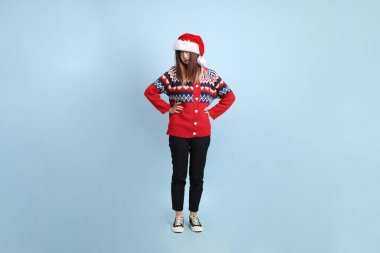 Asyalı bir kadın Noel ya da kışlık kıyafetler giyiyor ve Noel Baba şapkası takıyor. Mavi arka planda öfkeli ve çığlıklar atan biri. Noel Baba.