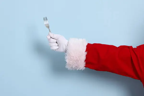 Mavi arka planda izole edilmiş çatal tutan Noel Baba 'nın yakın çekimi. Mutlu Noeller..