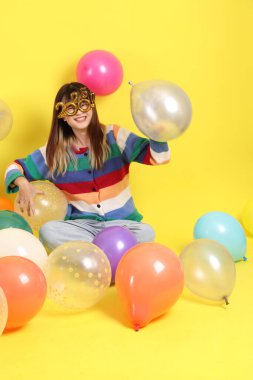 2025 numarayla renkli kışlık kıyafetler giyen Asyalı bir kadın. Yeni yıl için iki bin yirmi beş süslü gözlük. Sarı, kusursuz balon arka planında izole edilmiş..