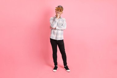 2025 numaralı sıradan görünüşlü Asyalı son sınıf öğrencisi. İki bin yirmi beş yeni yıl gözlüğü. Pembe arka planda izole edilmiş düşünce jesti..