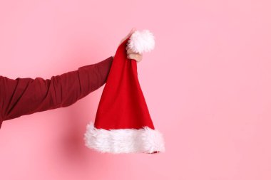 Resmi ve sıradan kırmızı tişörtlü Noel Baba şapkası giyen pembe bir arka planda izole edilmiş bir grup adam. Mutlu noeller. Xmas