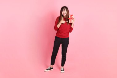 Kırmızı tişört giyen Asyalı bir kadın ya da pembe arka planda izole edilmiş hediyeler tutan sıradan bir jest. Noel Baba, Z Geni