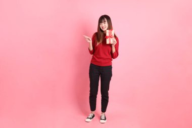 Kırmızı tişört giyen Asyalı bir kadın ya da pembe arka planda izole edilmiş hediyeler tutan sıradan bir jest. Noel Baba, Z Geni