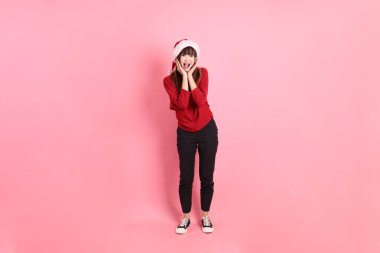 Asian woman wearing red t-shirt or casual clothes with Santa Claus cap with gesture of surprise, Wow and impressive isolated on pink background. Santy, Gen Z clipart