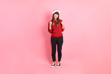 Asian woman wearing red t-shirt or casual clothes with Santa Claus cap with gesture of yes, excited, celebrating isolated on pink background. Santy, Gen Z clipart