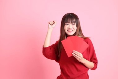 Mutlu Çin Yeni Yılı, pembe arka planda Çin kırmızısı zarflar tutan kırmızı tişörtlü Asyalı bir kadın. Gen Z