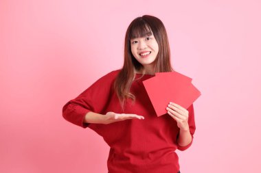 Mutlu Çin Yeni Yılı, pembe arka planda Çin kırmızısı zarflar tutan kırmızı tişörtlü Asyalı bir kadın. Gen Z