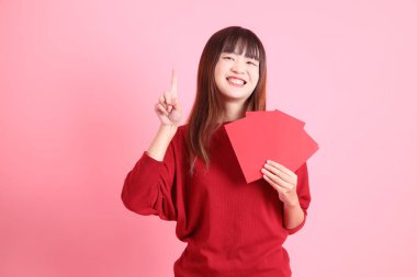 Mutlu Çin Yeni Yılı, pembe arka planda Çin kırmızısı zarflar tutan kırmızı tişörtlü Asyalı bir kadın. Gen Z