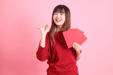 Mutlu Çin Yeni Yılı, pembe arka planda Çin kırmızısı zarflar tutan kırmızı tişörtlü Asyalı bir kadın. Gen Z