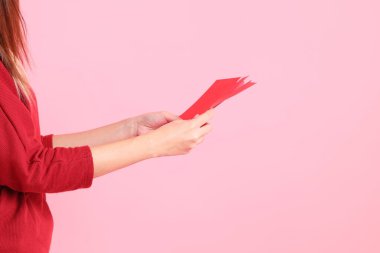 Mutlu Çin Yeni Yılları, pembe arka planda Çin kırmızı zarfları tutan kırmızı tişörtlü Asyalı bir kadının eli.. 