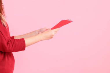 Mutlu Çin Yeni Yılları, pembe arka planda Çin kırmızı zarfları tutan kırmızı tişörtlü Asyalı bir kadının eli.. 