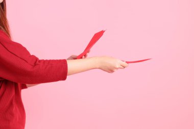 Mutlu Çin Yeni Yılları, pembe arka planda Çin kırmızı zarfları tutan kırmızı tişörtlü Asyalı bir kadının eli.. 