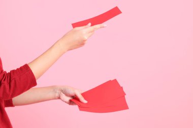 Mutlu Çin Yeni Yılları, pembe arka planda Çin kırmızı zarfları tutan kırmızı tişörtlü Asyalı bir kadının eli.. 