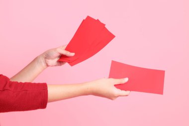 Mutlu Çin Yeni Yılları, pembe arka planda Çin kırmızı zarfları tutan kırmızı tişörtlü Asyalı bir kadının eli.. 