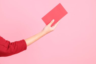 Mutlu Çin Yeni Yılları, pembe arka planda Çin kırmızı zarfları tutan kırmızı tişörtlü Asyalı bir kadının eli.. 
