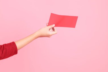 Mutlu Çin Yeni Yılları, pembe arka planda Çin kırmızı zarfları tutan kırmızı tişörtlü Asyalı bir kadının eli.. 