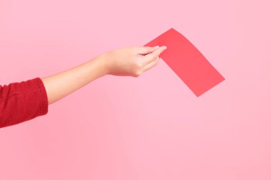 Mutlu Çin Yeni Yılları, pembe arka planda Çin kırmızı zarfları tutan kırmızı tişörtlü Asyalı bir kadının eli.. 