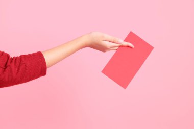 Mutlu Çin Yeni Yılları, pembe arka planda Çin kırmızı zarfları tutan kırmızı tişörtlü Asyalı bir kadının eli.. 