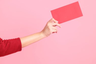 Mutlu Çin Yeni Yılları, pembe arka planda Çin kırmızı zarfları tutan kırmızı tişörtlü Asyalı bir kadının eli.. 