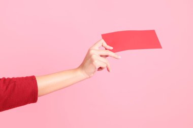Mutlu Çin Yeni Yılları, pembe arka planda Çin kırmızı zarfları tutan kırmızı tişörtlü Asyalı bir kadının eli.. 