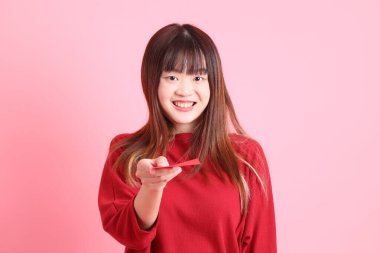 Mutlu Çin Yeni Yılı, pembe arka planda Çin kırmızısı zarflar tutan kırmızı tişörtlü Asyalı bir kadın. Gen Z