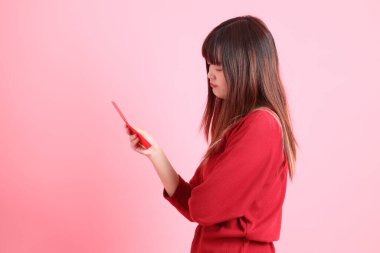 Mutlu Çin Yeni Yılı, pembe arka planda Çin kırmızısı zarflar tutan kırmızı tişörtlü Asyalı bir kadın. Gen Z