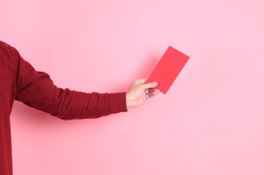 Mutlu Çin Yeni Yılı, resmi ve sıradan kırmızı tişörtlü Asyalı son sınıf öğrencisi pembe arka planda Çin kırmızısı zarflar tutuyor..  