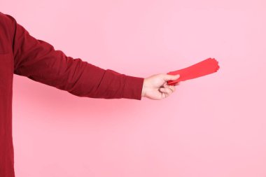 Mutlu Çin Yeni Yılı, resmi ve sıradan kırmızı tişörtlü Asyalı son sınıf öğrencisi pembe arka planda Çin kırmızısı zarflar tutuyor..  