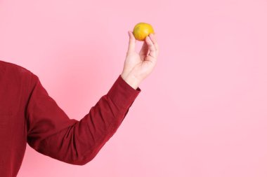 Mutlu Çin Yeni Yılları, resmi ve sıradan kırmızı tişörtlü Asyalı son sınıf öğrencisi. Pembe arka planda, el ele tutuşan Mandalina ya da Turuncu..  