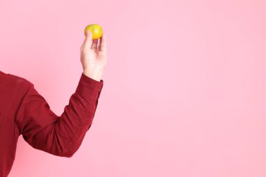 Mutlu Çin Yeni Yılları, resmi ve sıradan kırmızı tişörtlü Asyalı son sınıf öğrencisi. Pembe arka planda, el ele tutuşan Mandalina ya da Turuncu..  