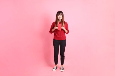 Mutlu Çin Yeni Yılı, pembe arka planda Çin kırmızısı zarflar tutan kırmızı tişörtlü Asyalı bir kadın. Gen Z