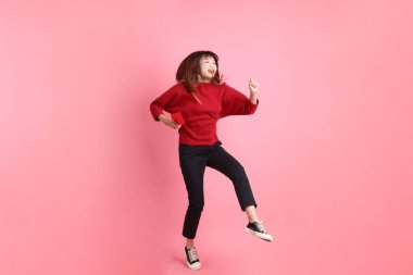 Mutlu Çin Yeni Yılı, kırmızı tişörtlü Asyalı genç bir kadın elinde Çin kırmızısı zarflar tutarken pembe arka planda izole bir şekilde zıplıyor. Gen Z