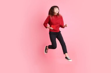 Mutlu Çin Yeni Yılı, kırmızı tişörtlü Asyalı genç bir kadın elinde Çin kırmızısı zarflar tutarken pembe arka planda izole bir şekilde zıplıyor. Gen Z