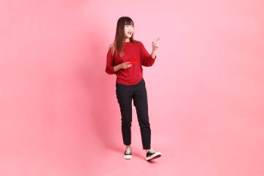 Mutlu Çin Yeni Yılı, kırmızı günlük tişörtlü Asyalı genç bir kadın elinde Çin kırmızısı zarflarla pembe arka planda tek başına yürüyor. Gen Z