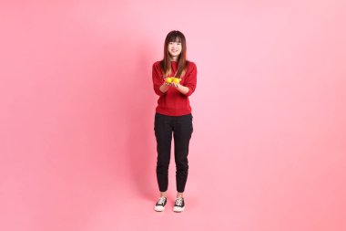 Mutlu Çin Yeni Yılı, pembe arka planda, elinde Mandalina ya da Portakal tutan kırmızı günlük Asyalı kadın tişörtü. Gen Z