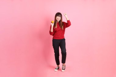 Mutlu Çin Yeni Yılı, pembe arka planda, elinde Mandalina ya da Portakal tutan kırmızı günlük Asyalı kadın tişörtü. Gen Z