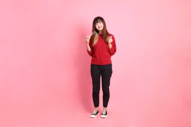 Mutlu Çin Yeni Yılı, pembe arka planda izole edilmiş plastik çubuklarla el ele tutuşan kırmızı günlük Asyalı kadın tişörtü. Gen Z