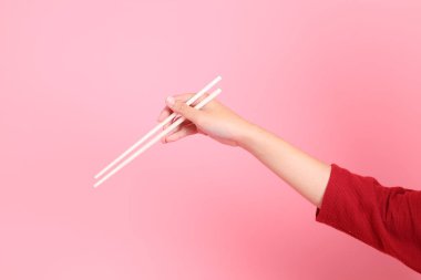 Mutlu Çin Yeni Yılı, pembe arka planda izole edilmiş plastik çubuklarla el ele tutuşan kırmızı günlük Asyalı kadın tişörtü. Gen Z