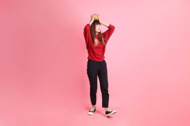 Mutlu Çin Yeni Yılı, kırmızı günlük tişörtlü Asyalı bir kadın altın rengi Çin kumbarası taşıyor pembe arka planda. Gen Z