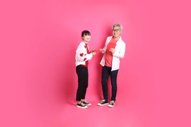 Mutlu Çin Yeni Yılı, Asyalı son sınıf öğrencisi ve genç bayan Noel Baba şapkası takıyor ve beyaz kalp şeklinde gömlek giyiyor. Üzerinde Çin kırmızısı zarflar taşıyor, pembe arka planda izole edilmiş..